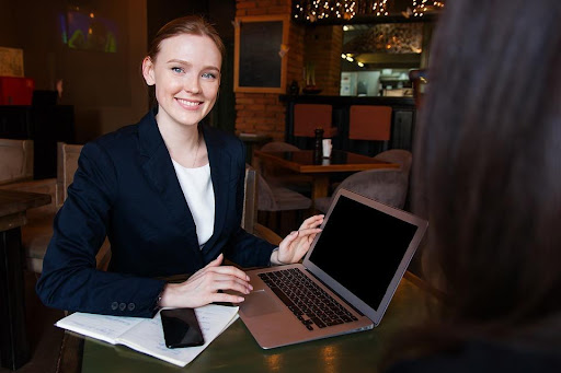 A woman holding a laptop and smiling
                                            