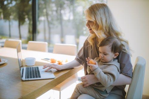 Woman working from home with baby in lap
                                            