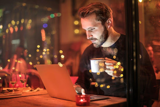 Person using laptop while holding a cup